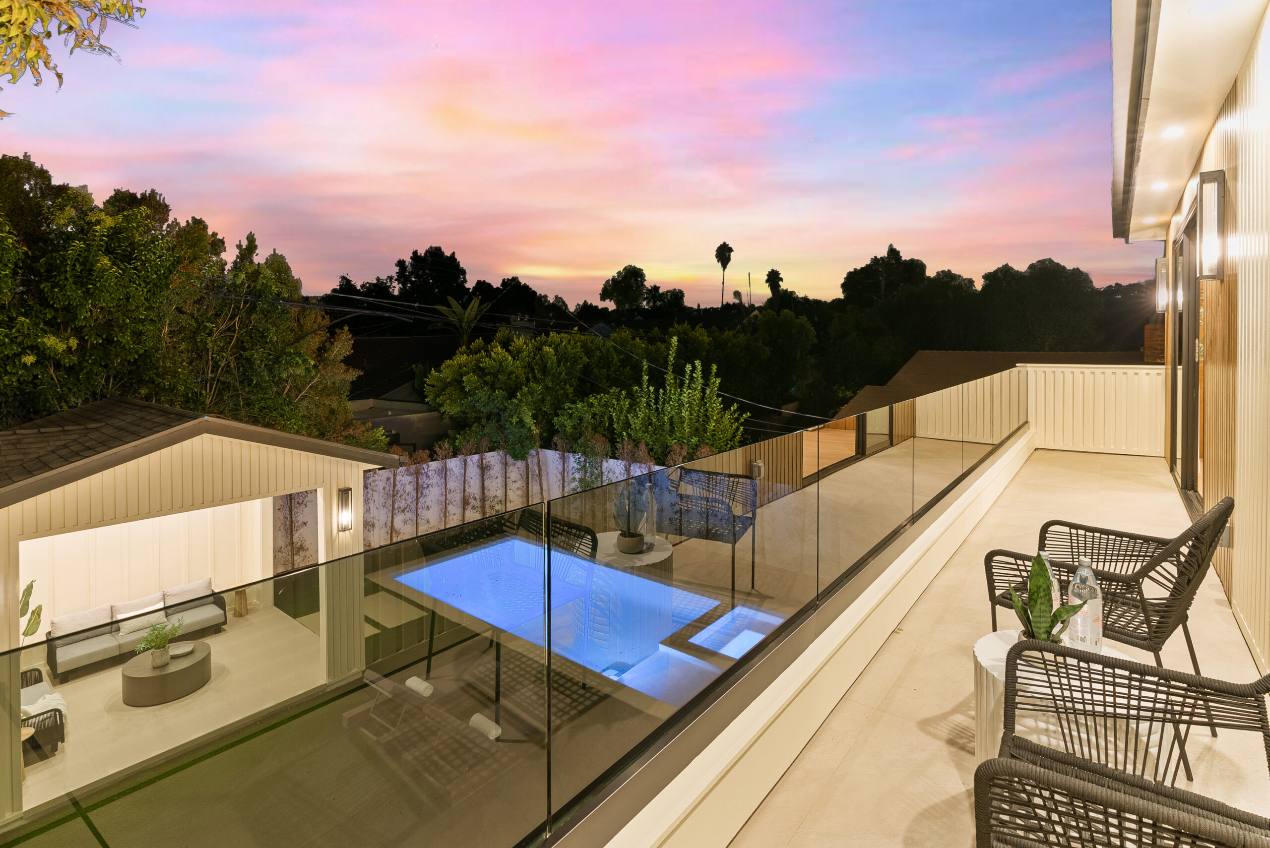 Modern balcony overlooking illuminated pool at sunset