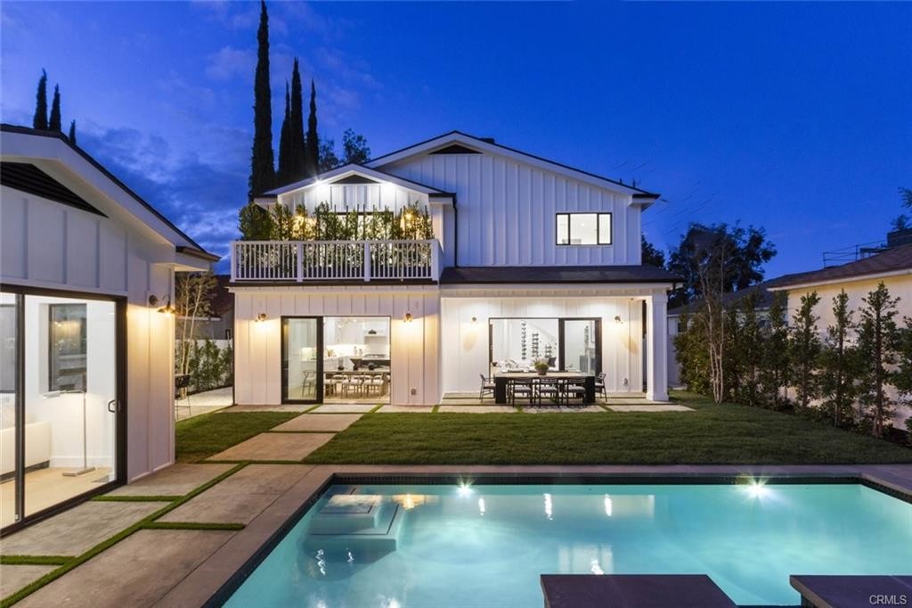 Modern two-story house with illuminated pool at night.