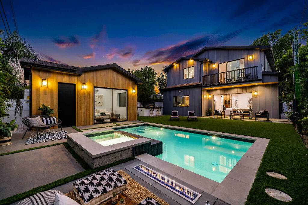 Modern backyard with pool and cozy seating under twilight sky.
