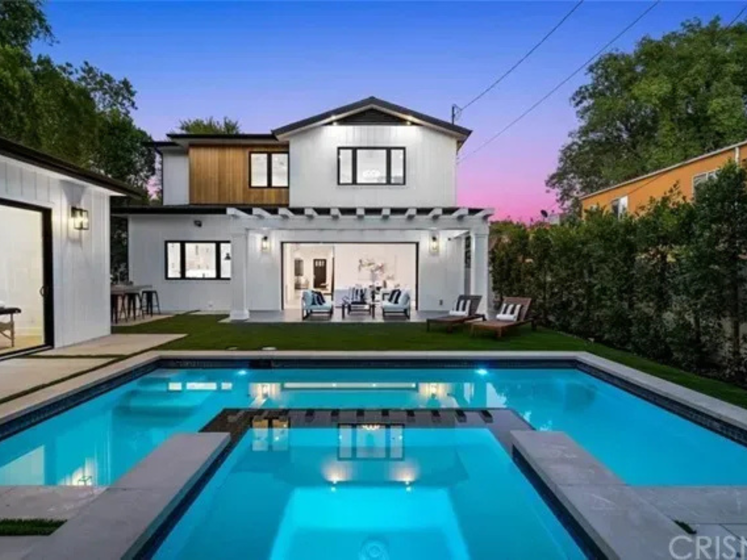 Modern house with a lit swimming pool at dusk.