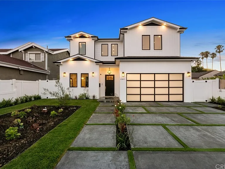 Modern two-story house with a well-lit entrance and landscaped front yard.