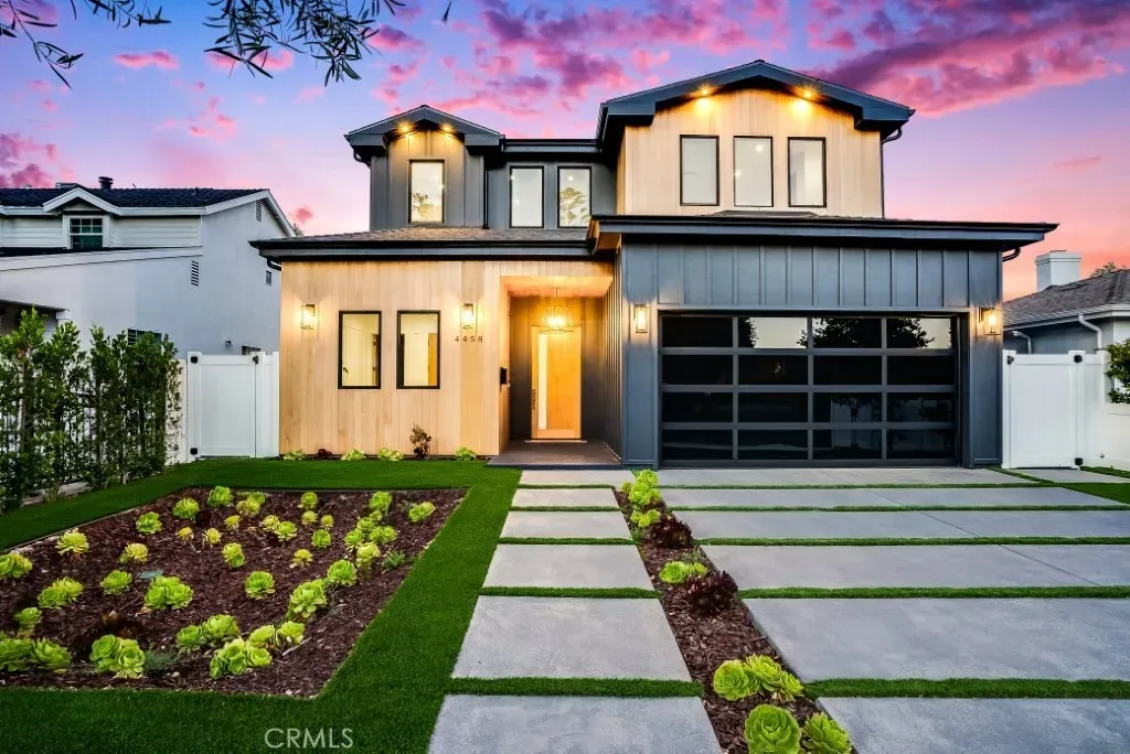 Modern two-story house with a beautifully landscaped front yard at sunset.