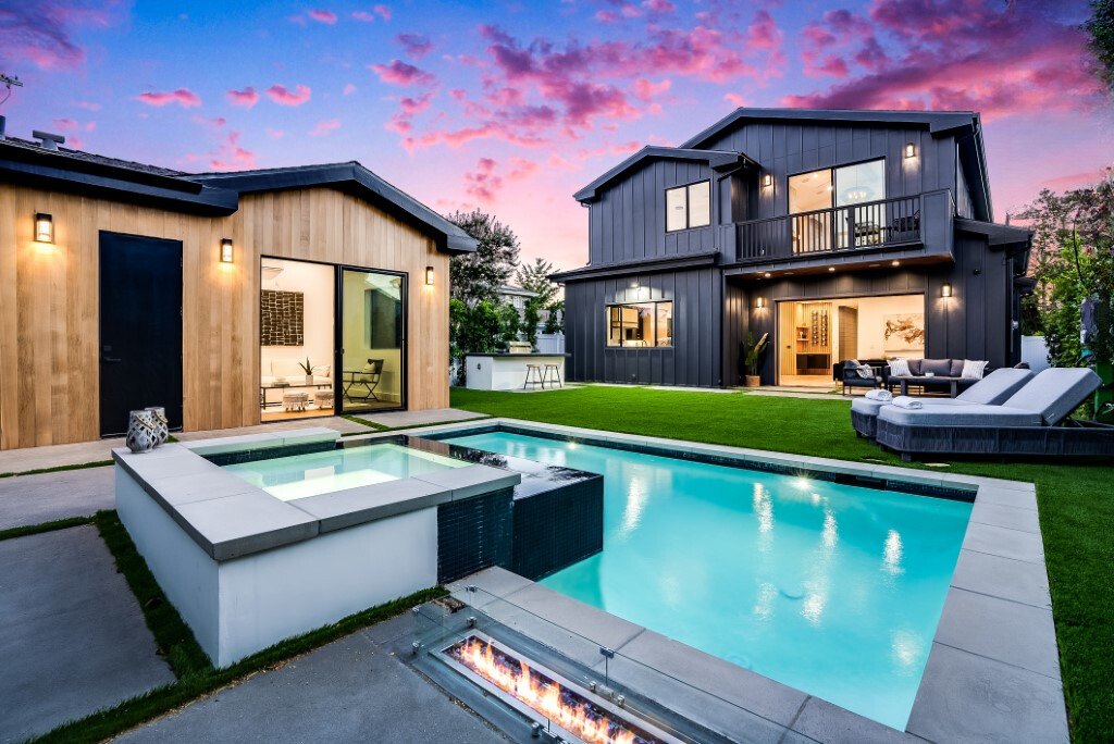 Rear elevation with lit pool and spa at dusk on a custom home by Luxury Home Builders Inc.